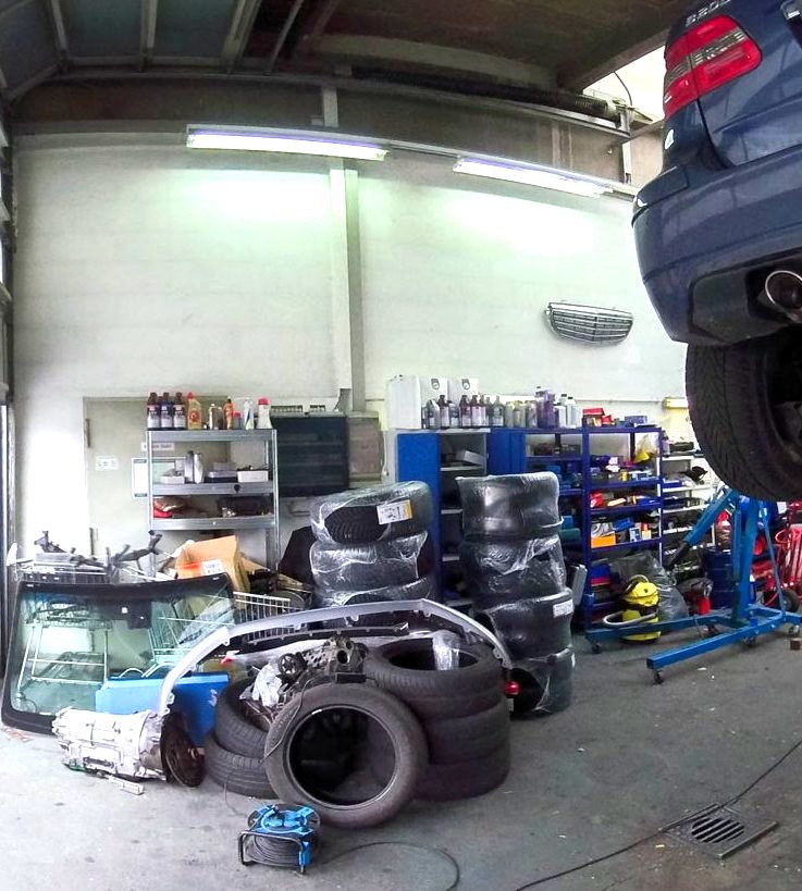 Regale mit Ölen und Ersatzteilen, Reifen und ein Fahrzeug auf der Hebebühne